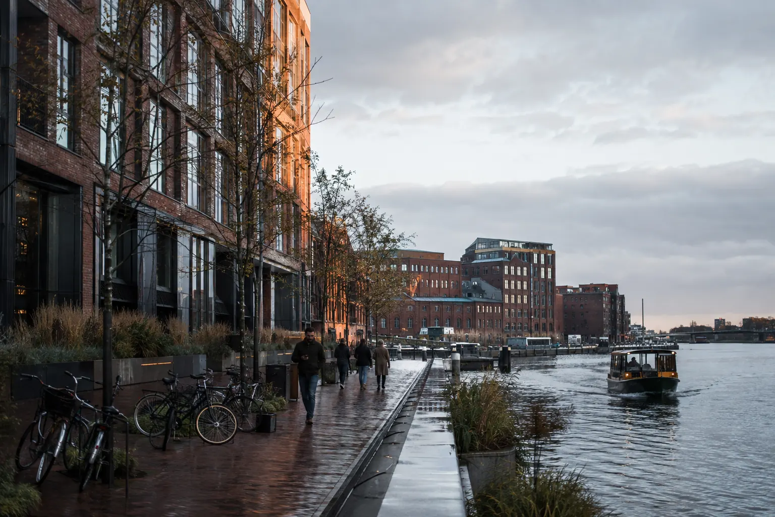 Natte kade met fietsen, bakstenen gebouwen en een kleine waterboot
